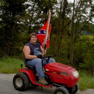 Some redneck driving down Hwy 37 on a lawn mower with a confederate flag that says, "Git'er done".